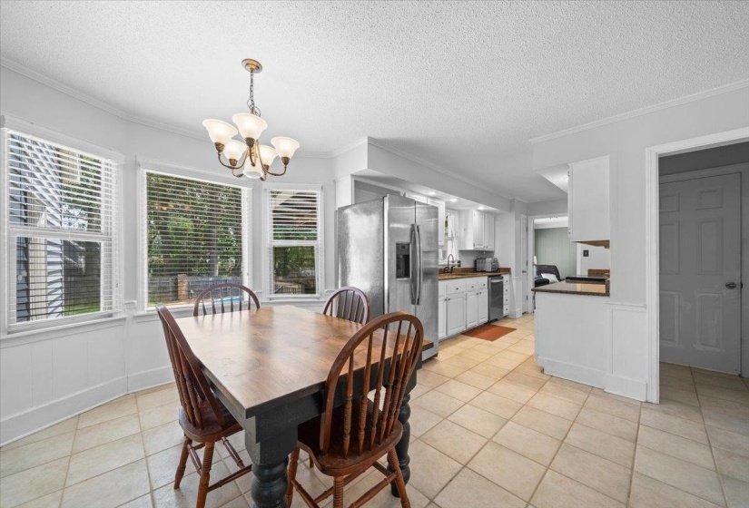Dining area featuring a chandelier, light tile patterned flooring, a textured ceiling, and ornamental molding