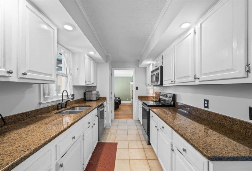 Kitchen with appliances with stainless steel finishes, crown molding, white cabinetry, recessed lighting, and dark stone countertops
