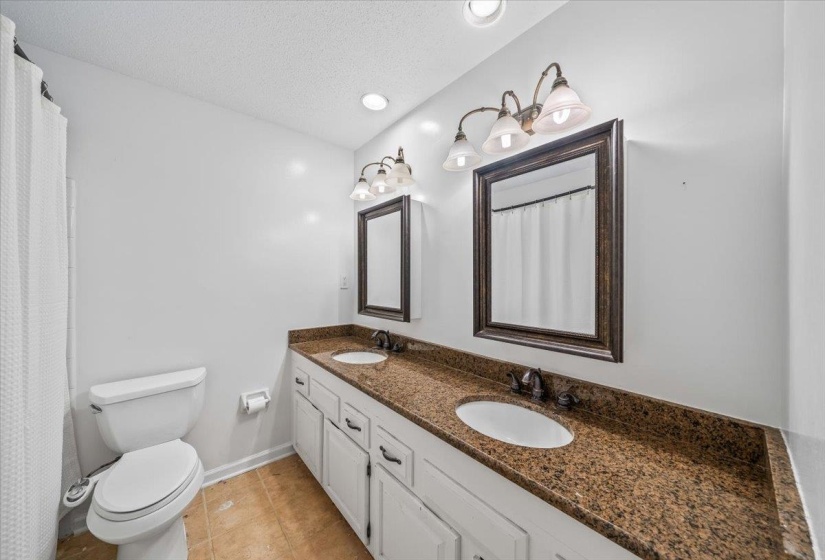 Full bathroom with double vanity, a textured ceiling, and tile patterned flooring