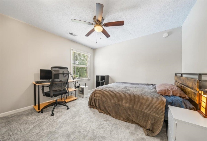 Carpeted bedroom featuring a textured ceiling and a ceiling fan