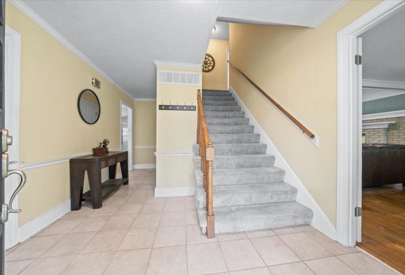 Staircase with tile patterned floors, crown molding, and a textured ceiling