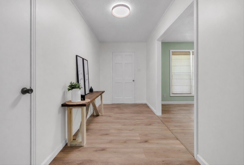 Hallway featuring light wood-style flooring, a textured ceiling, and ornamental molding