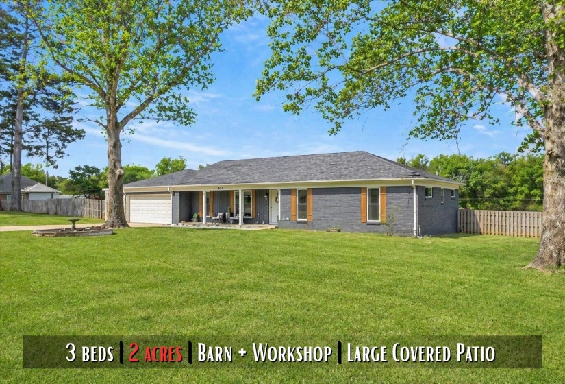 Ranch-style residence featuring a gray brick exterior, a covered front porch with white columns, a two-car garage, and wood shutters