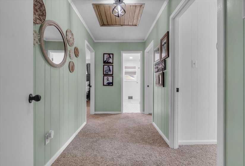 Hallway with cooling unit, crown molding, and light colored carpet