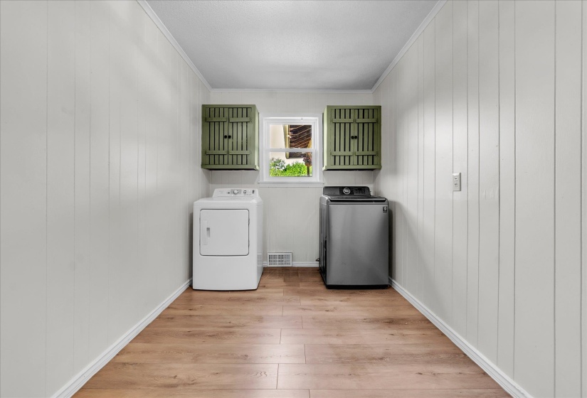 Laundry area with washing machine and clothes dryer, light wood finished floors, crown molding, and wood walls