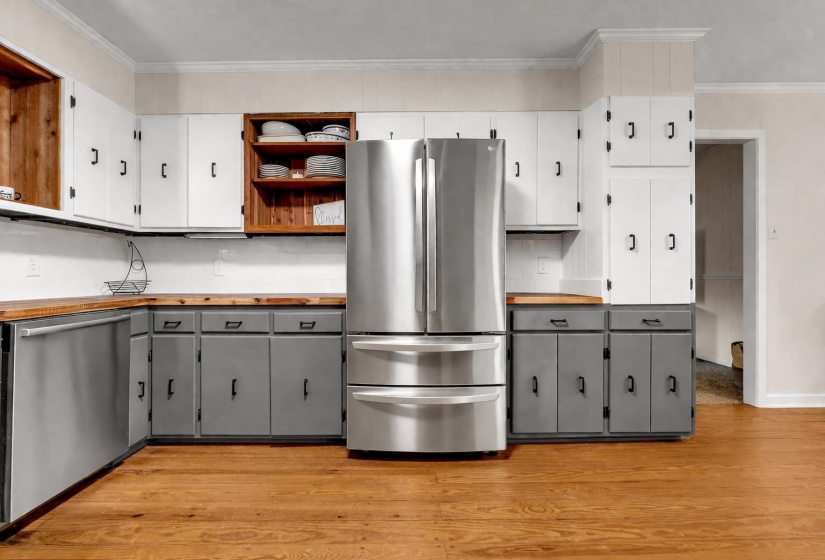 Kitchen with butcher block counters, stainless steel appliances, two tone cabinetry, ornamental molding, and open shelves