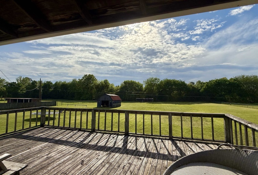 Wooden deck with a yard, a storage unit, and view of scattered trees