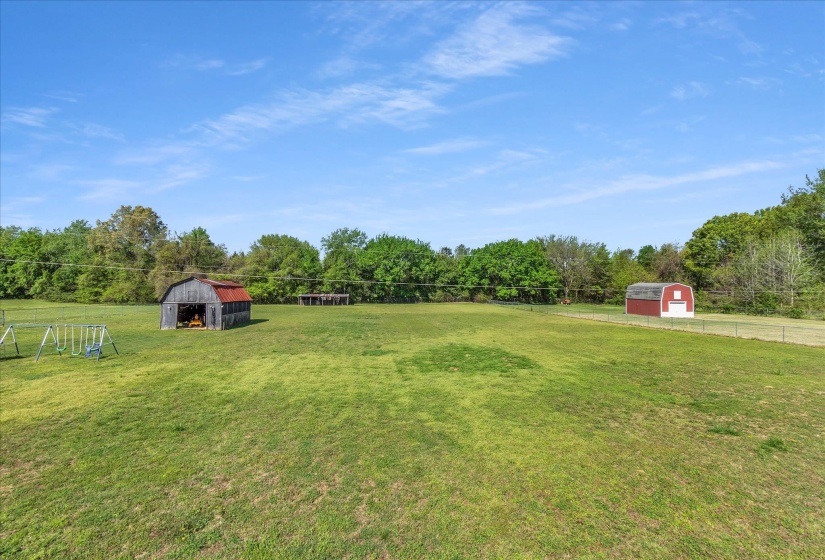 View of yard featuring a barn, an outdoor structure, and view of wooded area