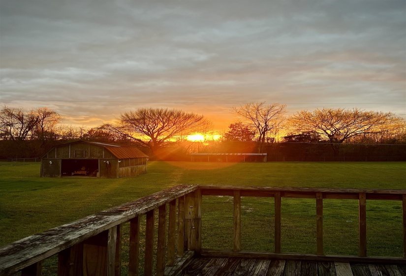 Deck at dusk featuring a lawn, an outbuilding, and a barn
