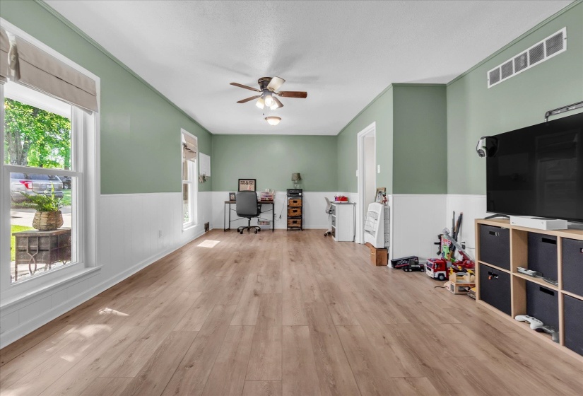 Home office with ceiling fan, light wood-style floors, and a wainscoted wall