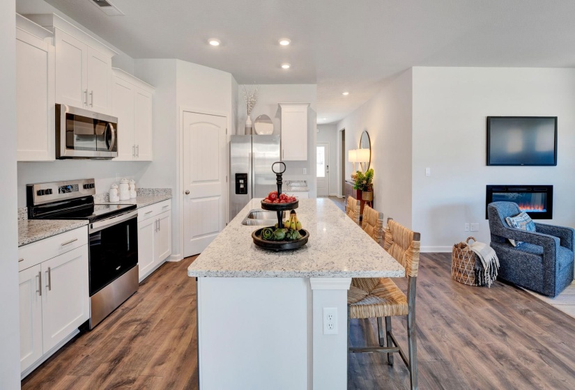 Kitchen with a center island with sink, stainless steel appliances, open floor plan, a kitchen bar, and white cabinetry