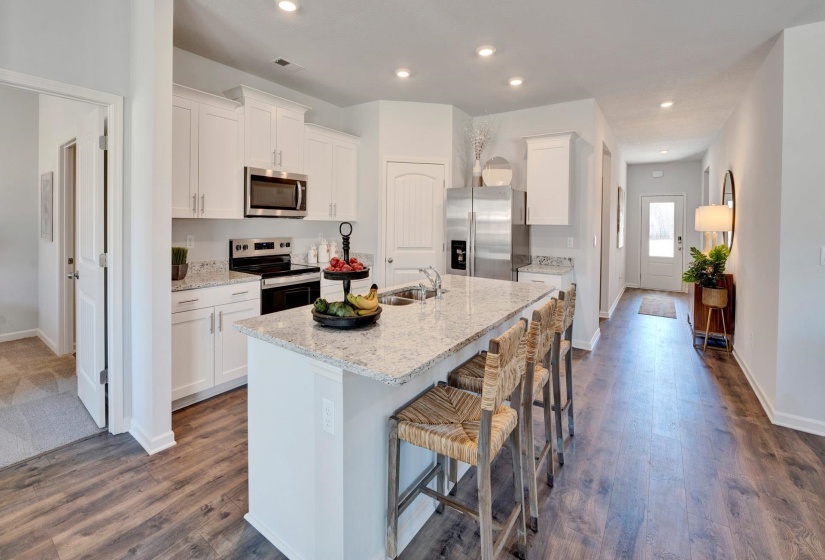 Kitchen featuring a kitchen bar, white cabinets, a center island with sink, stainless steel appliances, and recessed lighting