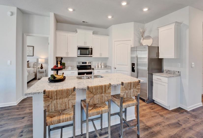 Kitchen featuring white cabinetry, light stone counters, stainless steel appliances, a kitchen bar, and recessed lighting