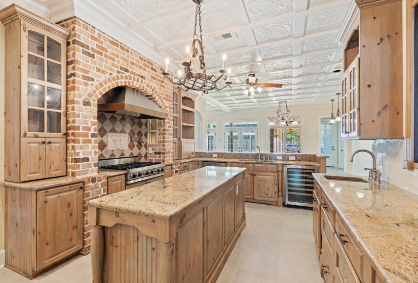 Kitchen featuring glass insert cabinets, light stone counters, a peninsula, beverage cooler, and an ornate ceiling