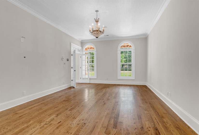 Unfurnished room featuring ornamental molding, wood finished floors, and a chandelier