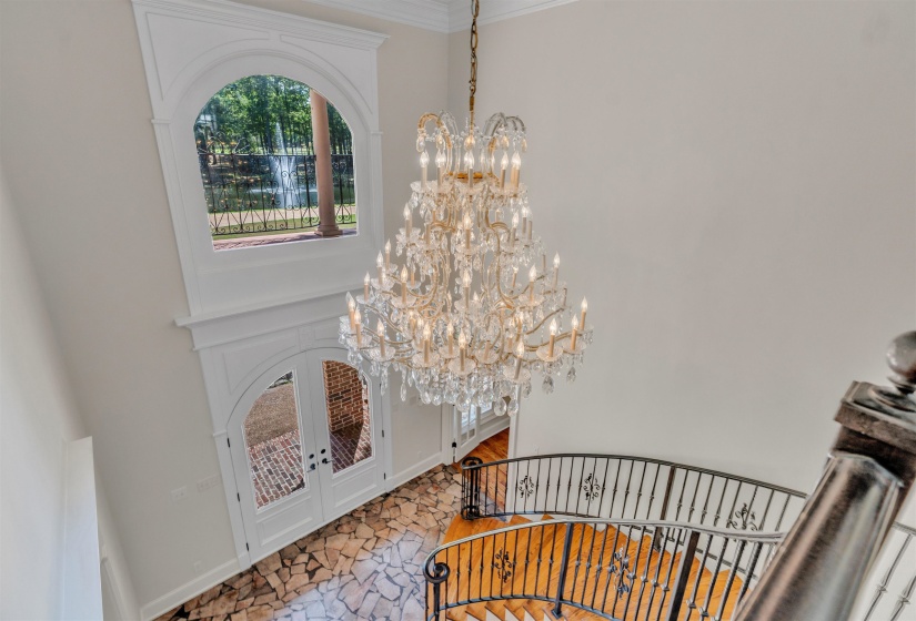 Foyer entrance with a chandelier, stairs, a high ceiling, french doors, and crown molding