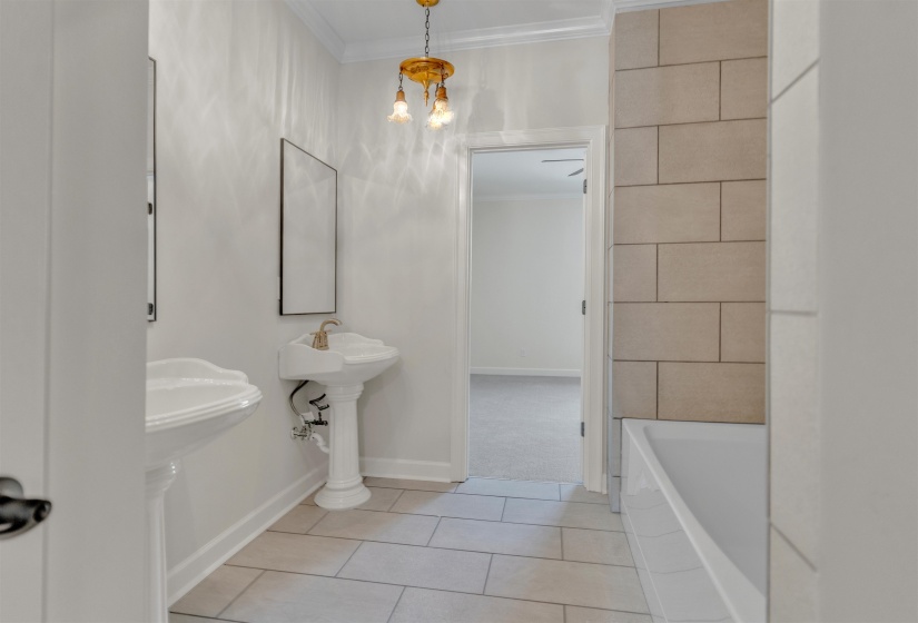 Bathroom featuring ornamental molding, a bathtub, light tile patterned floors, and a chandelier