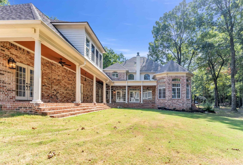 Rear view of house with a ceiling fan, brick siding, a yard, and french doors