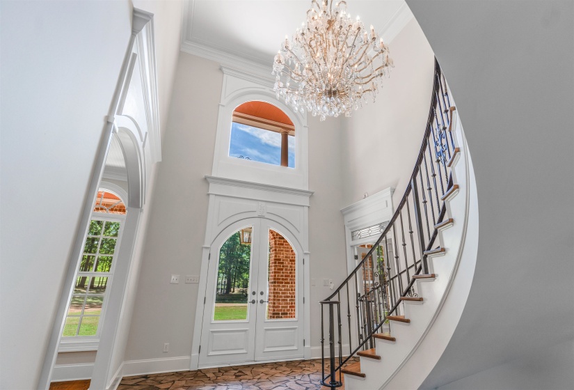 Entrance foyer featuring crown molding, a towering ceiling, french doors, a chandelier, and stairs