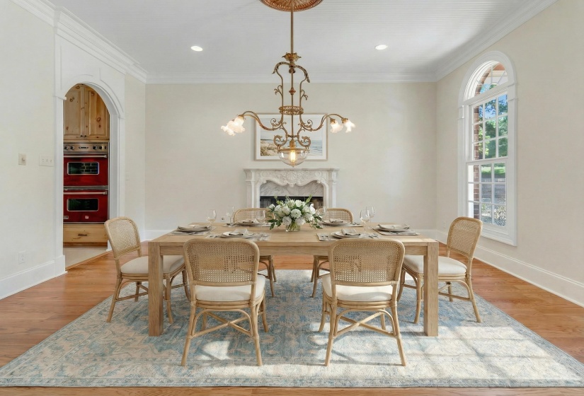 Dining space with light wood-type flooring, ornamental molding, a chandelier, arched walkways, and a high end fireplace