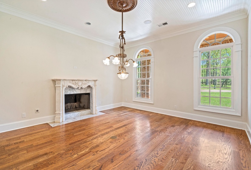 Unfurnished living room featuring wood finished floors, ornamental molding, a fireplace, and a chandelier