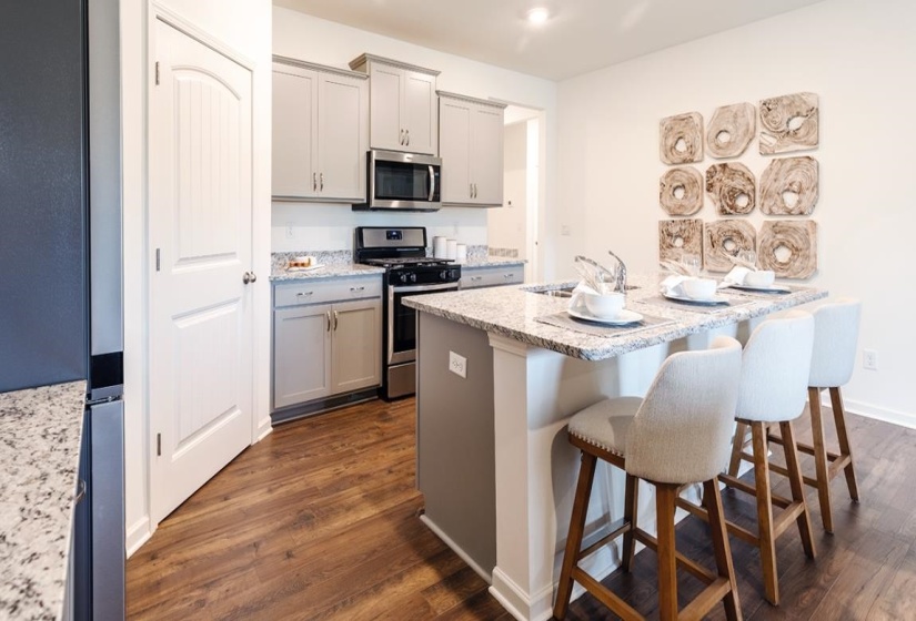 Kitchen featuring appliances with stainless steel finishes, gray cabinets, dark wood-style flooring, and a kitchen bar