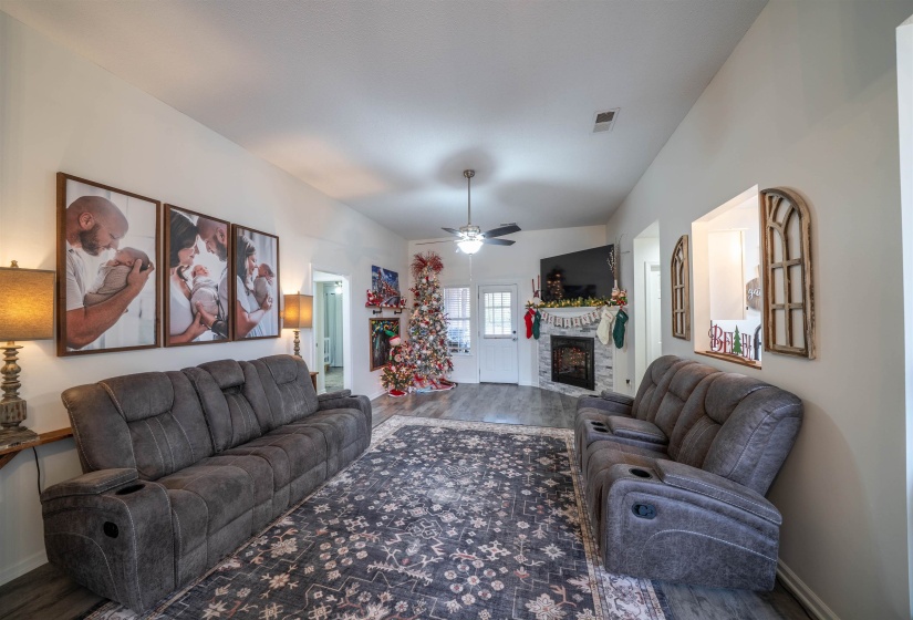 Living room featuring a fireplace, a ceiling fan, and wood finished floors