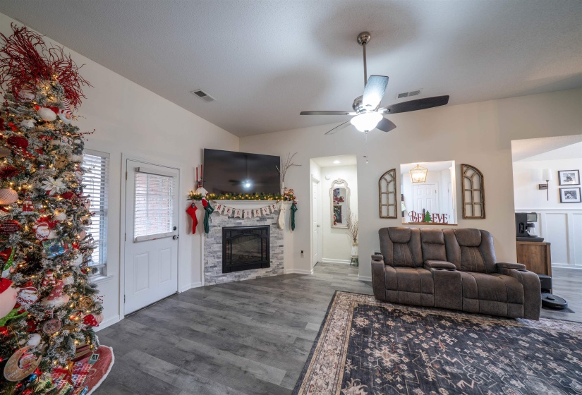 Living room with ceiling fan, dark wood-type flooring, and a fireplace