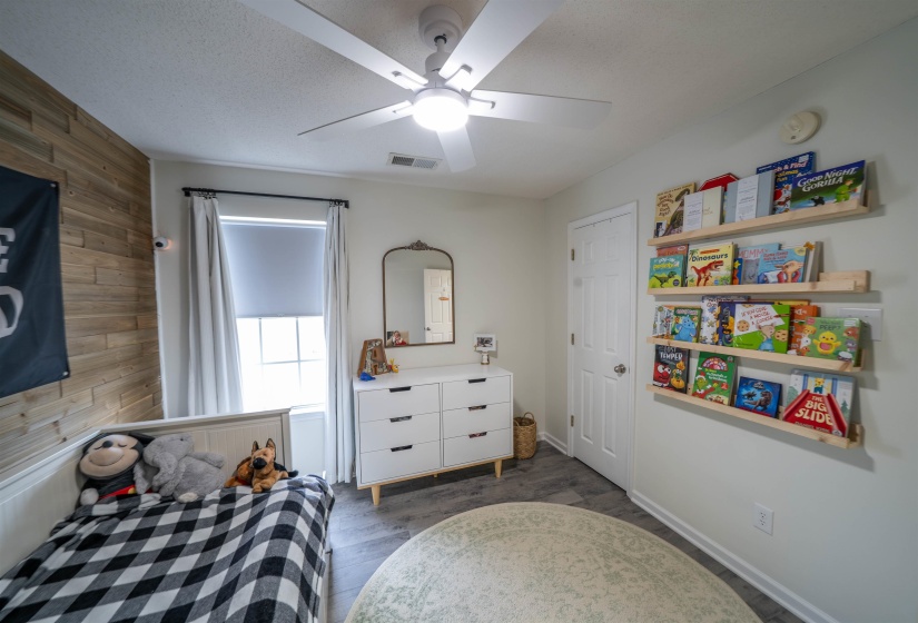 Bedroom featuring wooden walls, dark wood-type flooring, a ceiling fan, and a textured ceiling