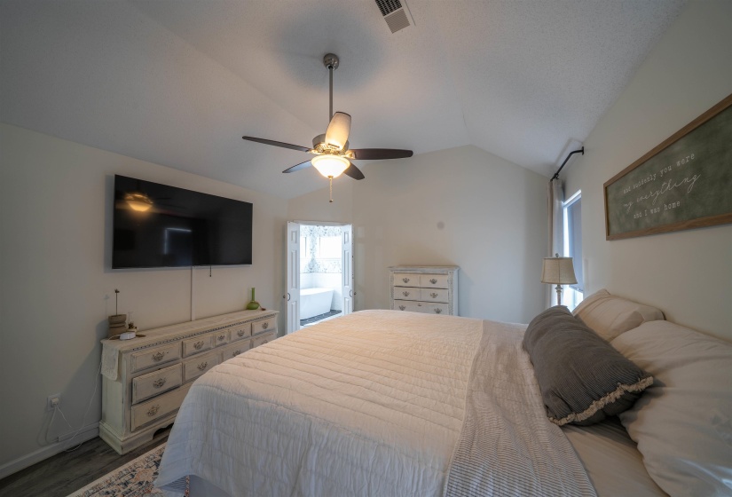 Bedroom with vaulted ceiling, ceiling fan, dark wood finished floors, and access to exterior