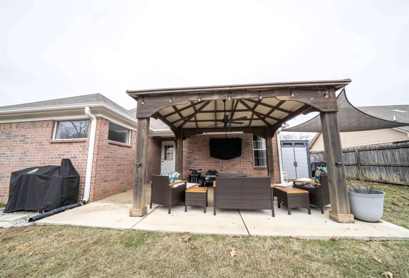 View of patio featuring an outdoor hangout area, ceiling fan, a gazebo, grilling area, and an outdoor structure