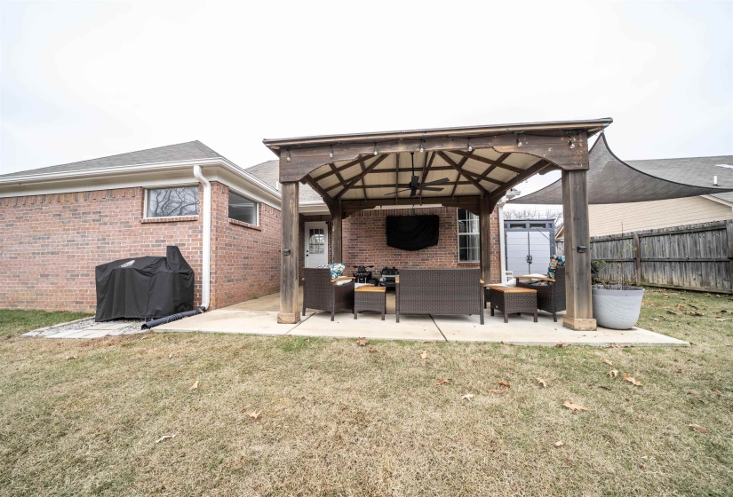 Rear view of property with ceiling fan, a gazebo, an outdoor hangout area, a patio area, and brick siding
