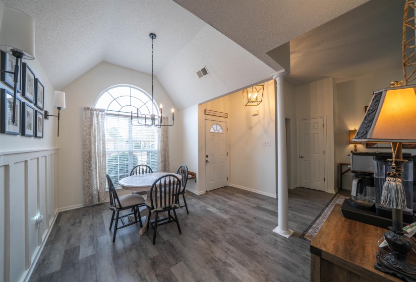 Dining room featuring ornate columns, a textured ceiling, a chandelier, lofted ceiling, and dark wood-style flooring