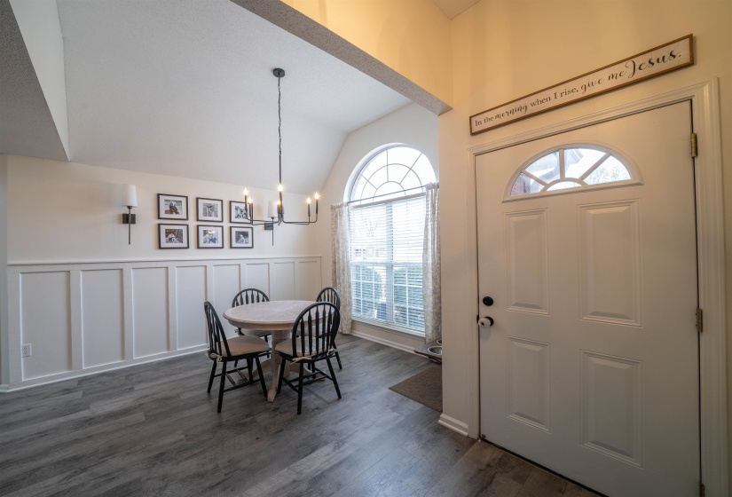 Foyer featuring a decorative wall, vaulted ceiling, a chandelier, dark wood-style floors, and a wainscoted wall