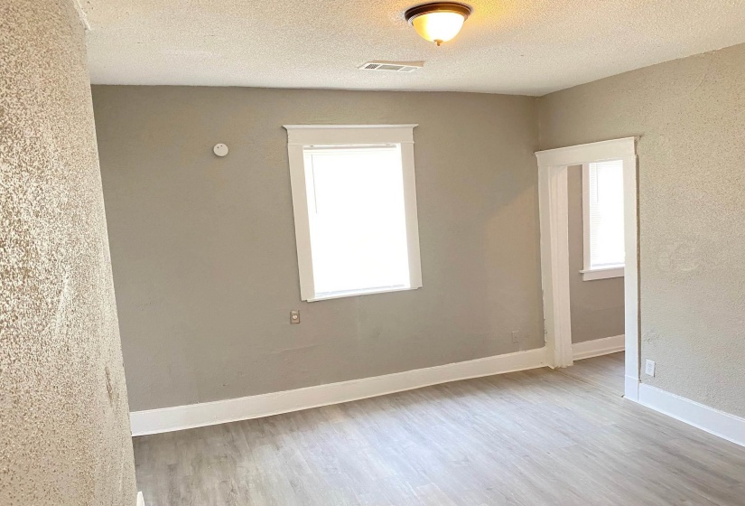 Unfurnished room with a textured wall, light wood-type flooring, and a textured ceiling