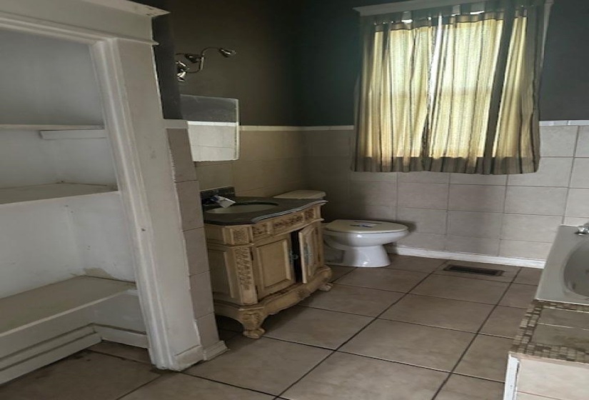 Full bathroom featuring vanity, a bath, light tile patterned floors, tile walls, and wainscoting