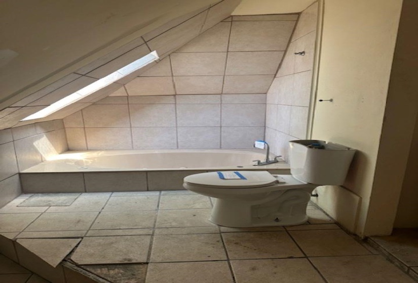 Bathroom featuring washtub / shower combination and light tile patterned flooring