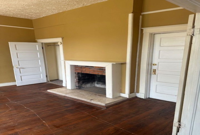 Unfurnished living room with dark wood-style floors, a fireplace, and a textured ceiling