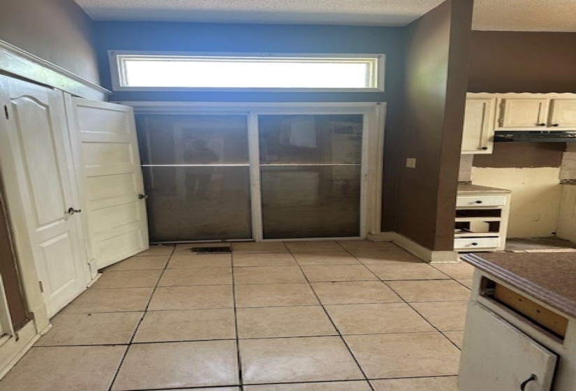 Doorway to outside featuring a textured ceiling, tile patterned floors, and healthy amount of natural light