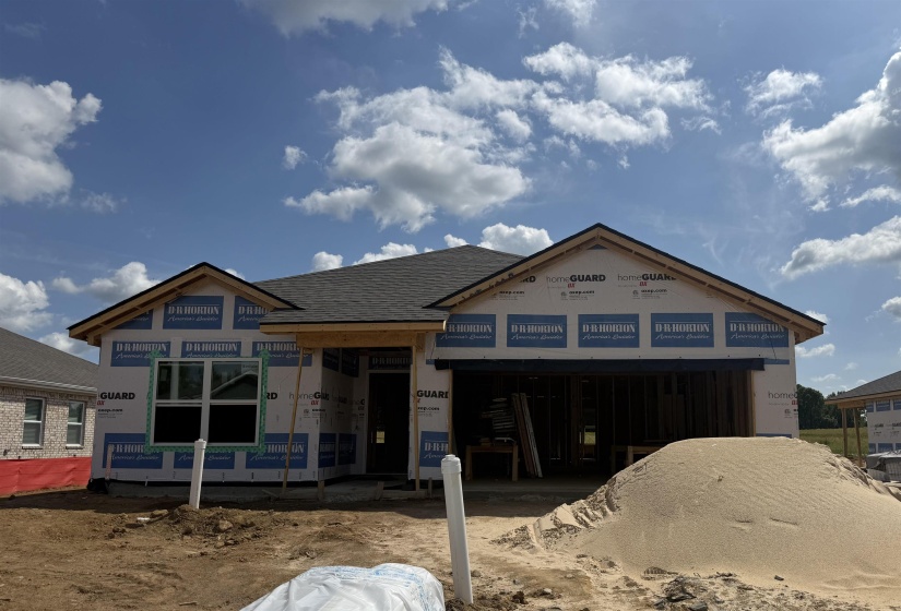 New construction home featuring a dark shingle roof, gabled rooflines, a framed garage opening, and installed window unit