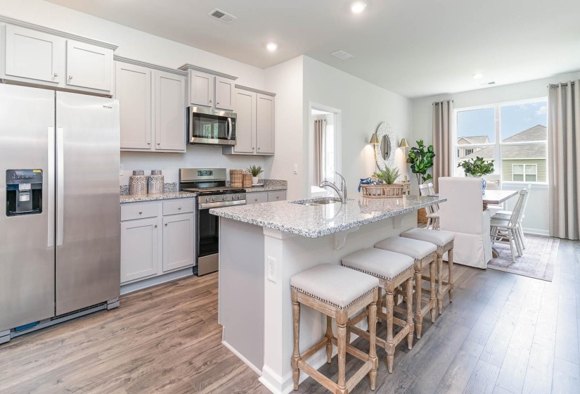 Kitchen featuring stainless steel appliances, light wood-style floors, a kitchen breakfast bar, light stone counters, and recessed lighting