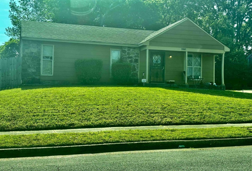 View of front of house featuring covered porch, stone siding, and a front lawn