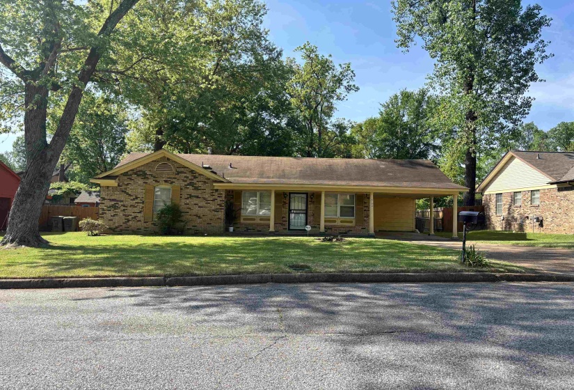 Single story home with brick siding, driveway, an attached carport, a porch, and a front yard