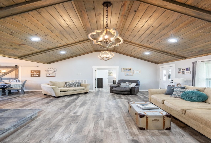 Living room featuring suspended lighting, a wood ceiling with exposed beams, and wood finished floors