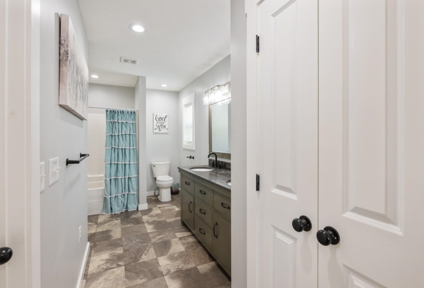 Bathroom featuring double vanity, shower / bath combo, and recessed lighting