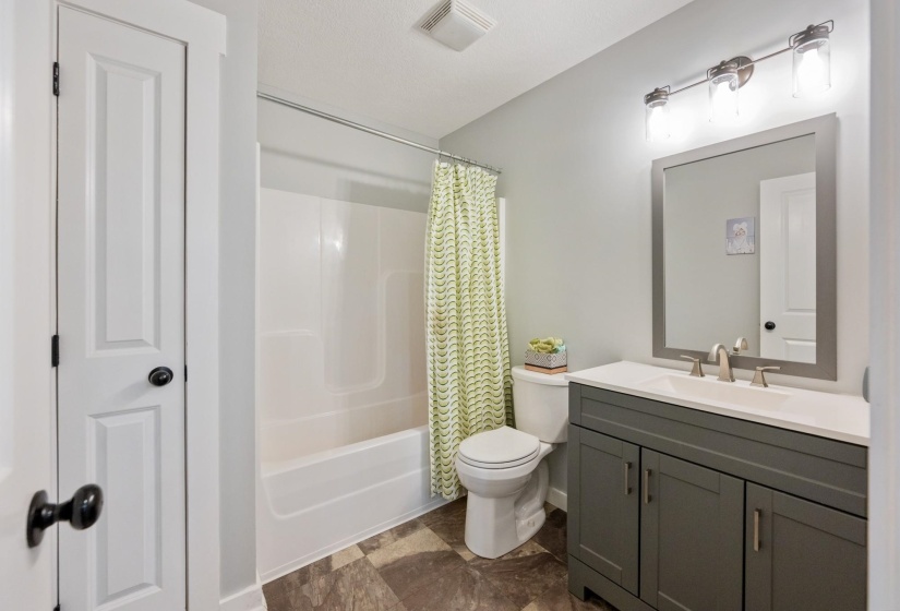 Full bath featuring vanity, shower / bath combo with shower curtain, and stone finish floors