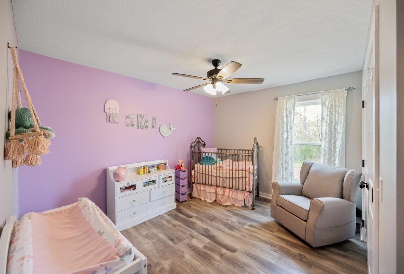 Bedroom with light wood-style floors, a crib, and ceiling fan