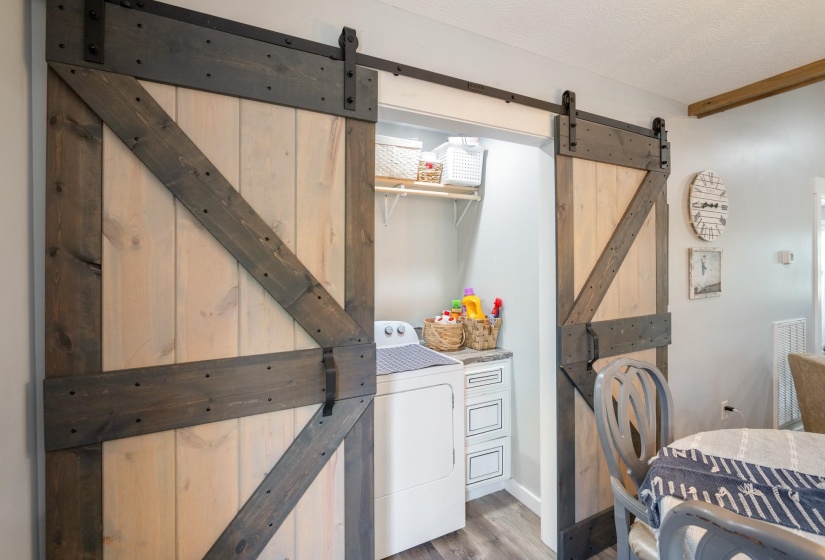 Laundry area featuring a barn door, washer / dryer, light wood-type flooring, and a textured ceiling
