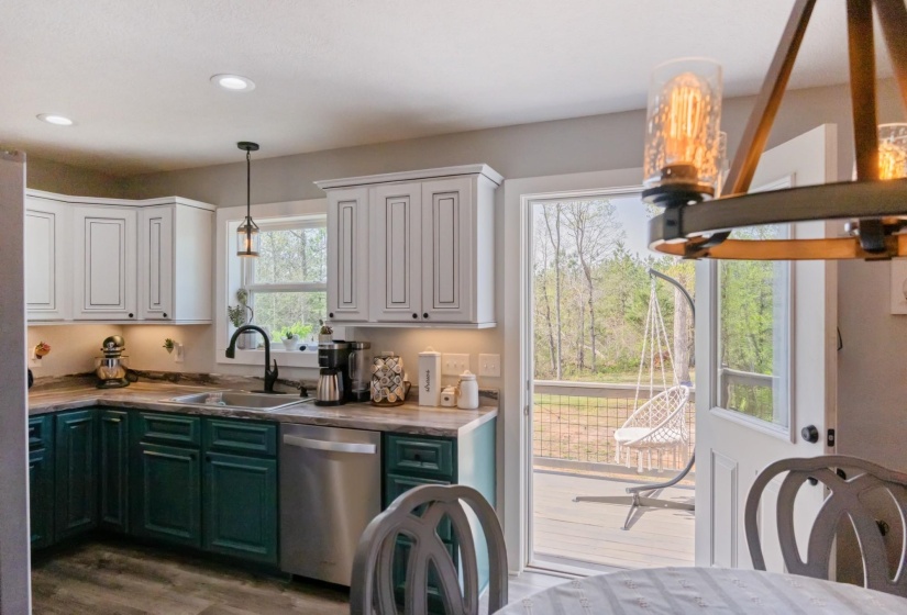 Dual tone kitchen featuring two tone color scheme, dishwasher, decorative light fixtures, light wood-style floors, and butcher block counters