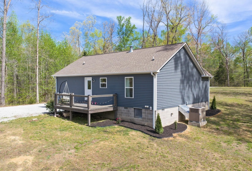 Rear view of property featuring a deck, roof with shingles, and a lawn